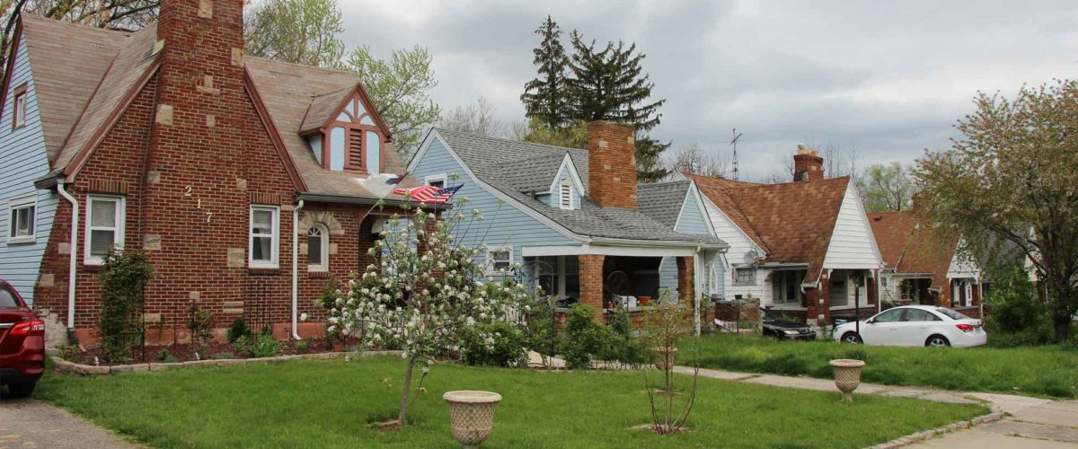 Tree-lined residential street in a Dayton, Ohio suburb with well-kept bungalow homes.