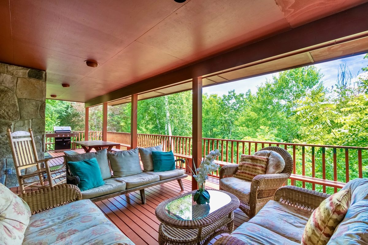 Wooden deck overlooking a forested mountain lake at a large vacation rental property.